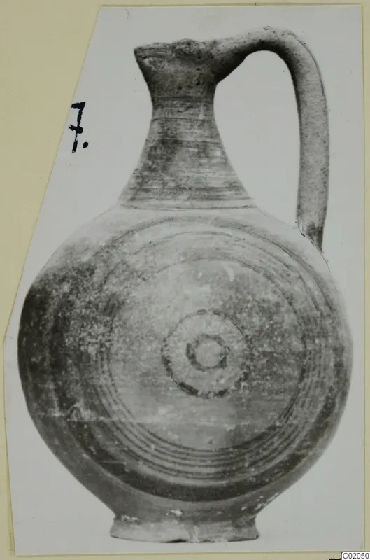 Pottery jug, Black-on-Red II-IV, with a tall neck, strap handle and concentric circles painted on its rounded body