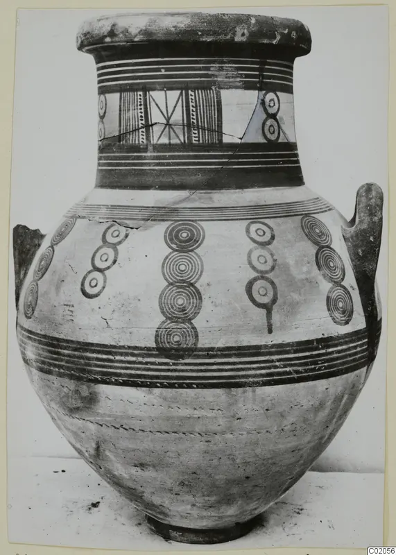 White Painted IV amphora with two handles, concentric circle motifs and painted bands, standing on a pale surface
