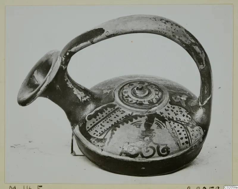 Pottery vessel with a flaring spout, tall loop handle and a painted head in profile on the body.