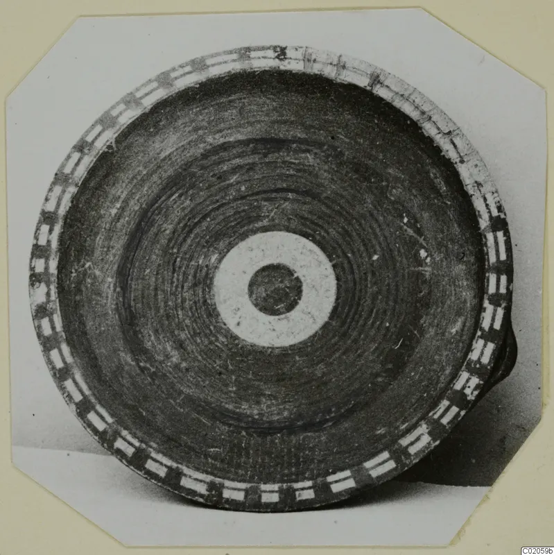 Pottery vessel seen from above, with a rim band of alternating rectangles and a central pale ring with a dark disc