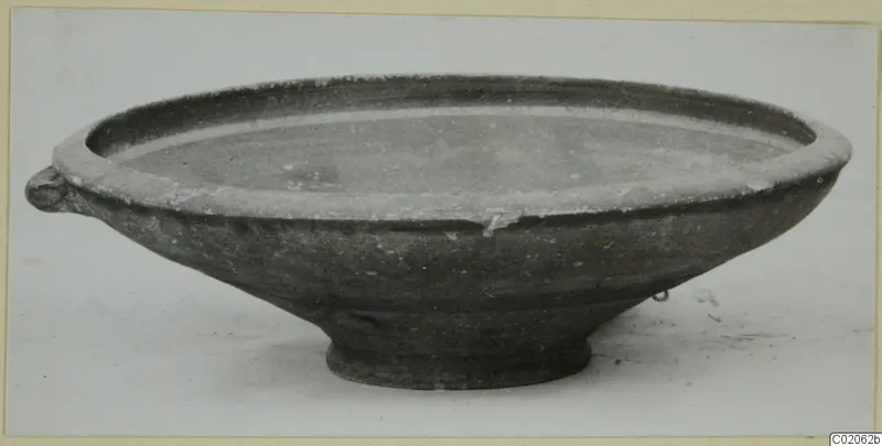 Shallow bowl with a small lug handle and a low ring foot, photographed from the side.
