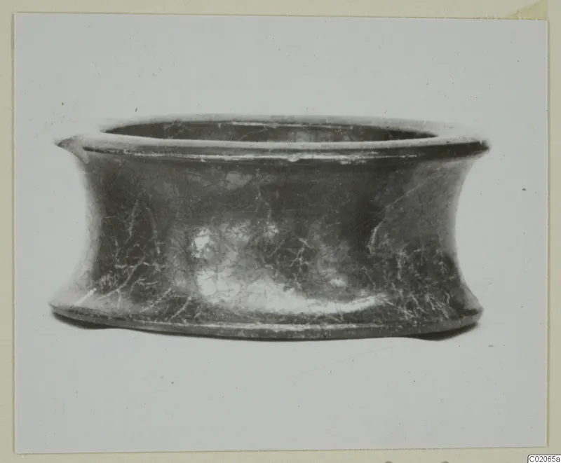 Black glazed ware bowl with a flaring rim and waisted sides, seen from the side