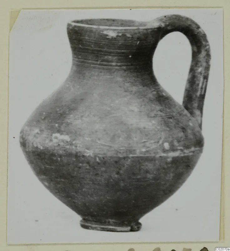 Round-bodied jug with a tall neck and a loop handle, photographed on a plain background.