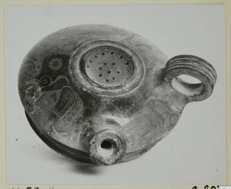Pottery lamp with a perforated filling disc, ribbed loop handle and short nozzle, with painted decoration