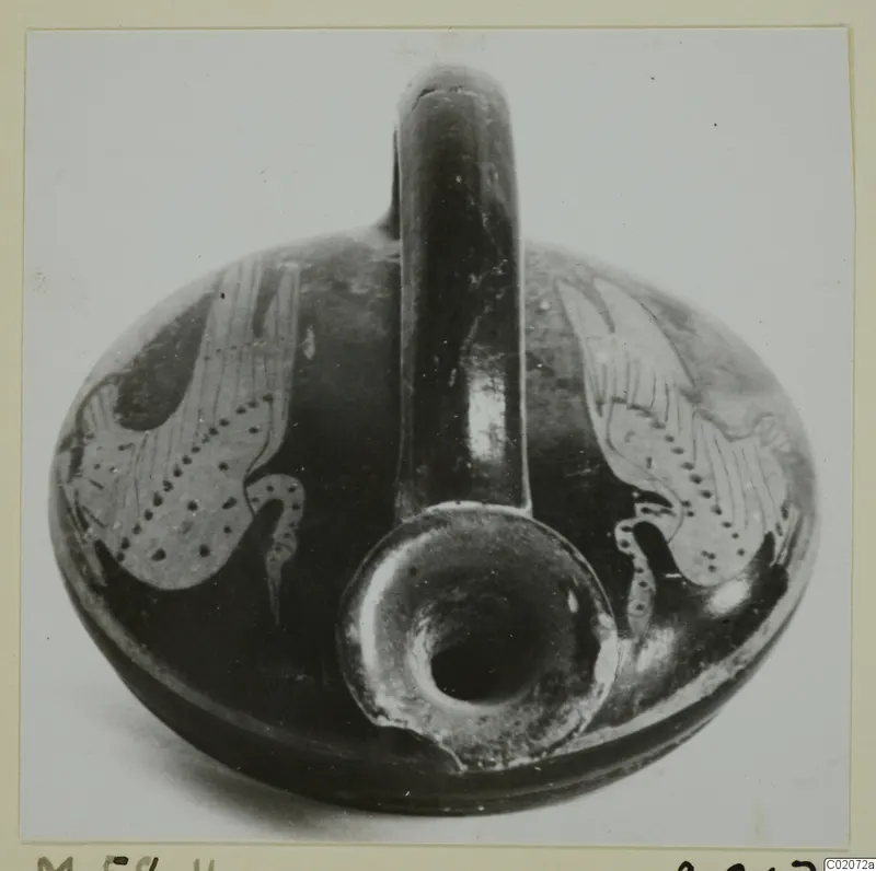 Round pottery vessel with a tall strap handle and dark glaze, with pale patterned panels on the body