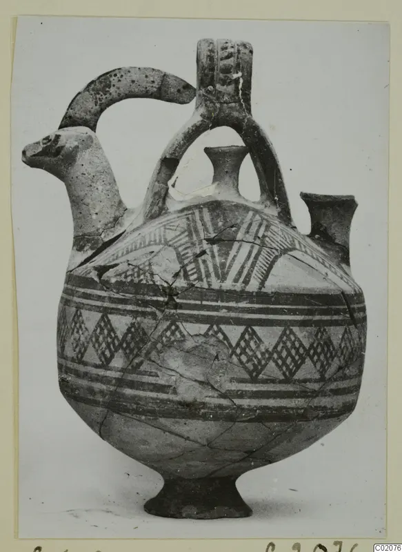 White Painted I jug with an animal-head spout, a second small spout and a looped handle, decorated with painted bands and hatched patterns.