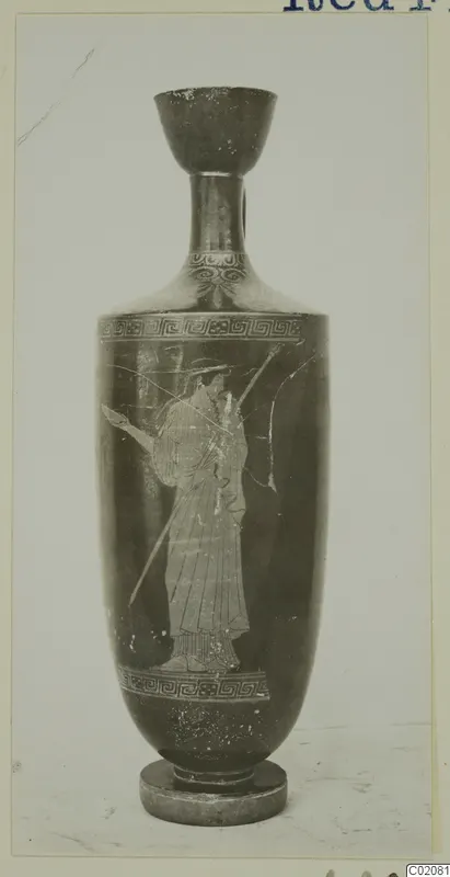 Tall vessel with a flaring mouth and a painted standing figure holding a spear, photographed against a grey backdrop
