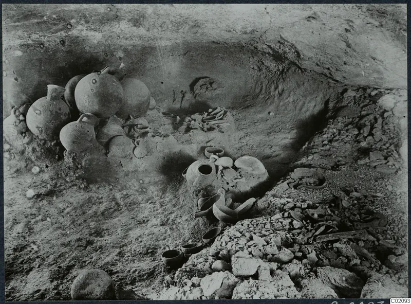 Tomb 6 at Ayios Iakovos during excavation, with several jugs, bowls and a skeleton in the chamber