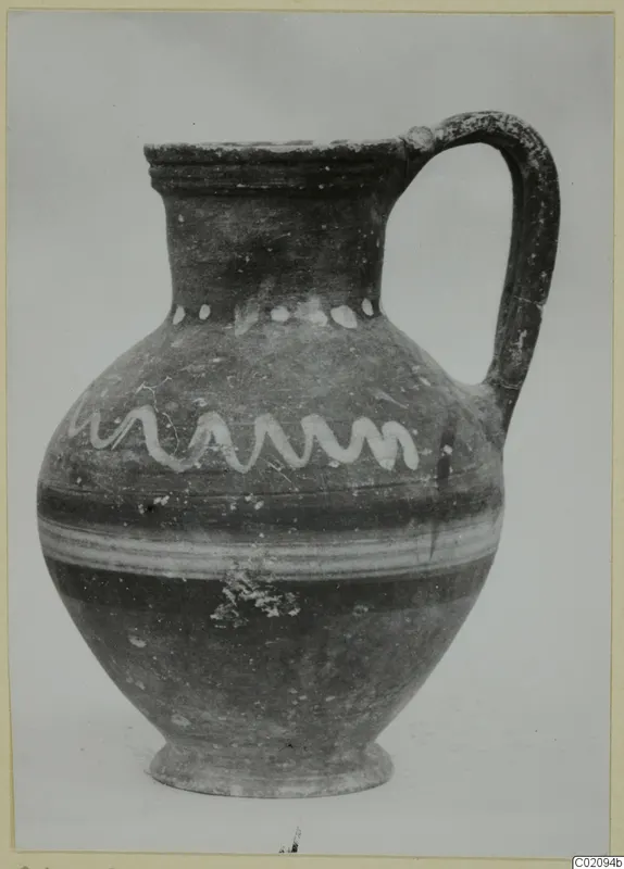 Jug with a strap handle, painted with a white wavy band and a row of white dots on the body