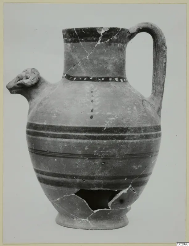 Pottery jug with a modelled animal-head spout and a strap handle, photographed against a plain background.