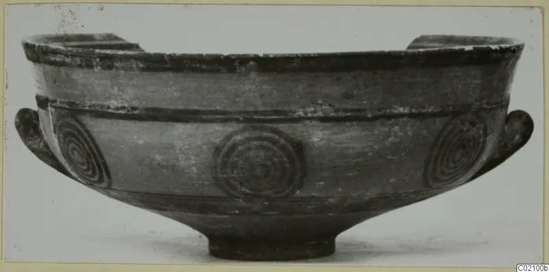 Pottery Black-on-Red bowl with two side handles and concentric circle motifs on the body, seen from the side