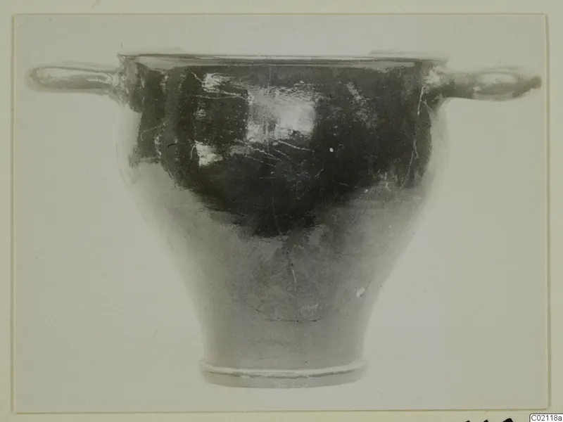 Black glazed pottery bowl with two horizontal handles and a flaring foot, seen from the side