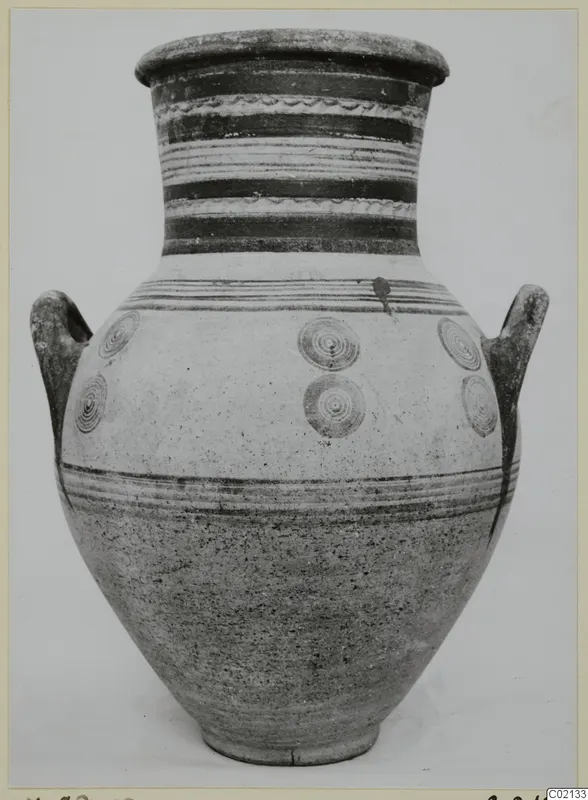 Large two-handled pottery jar with white slip, horizontal dark bands and concentric circle motifs.