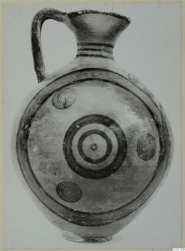 Black-on-red jug with a single handle, a ring-and-spiral decorated body and a flaring mouth, shown against a plain background.