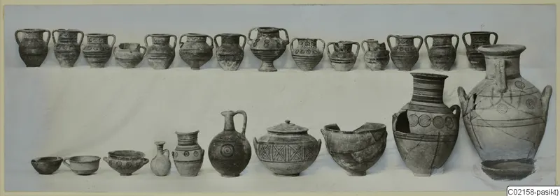 Two rows of pottery vessels from Marion, Tomb 79, with banded and circle decoration, set out on a white cloth