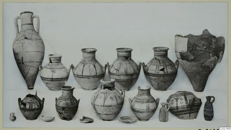Two rows of painted pottery vessels from Marion Tomb 97, jars, jugs and small juglets set out on a pale backdrop.