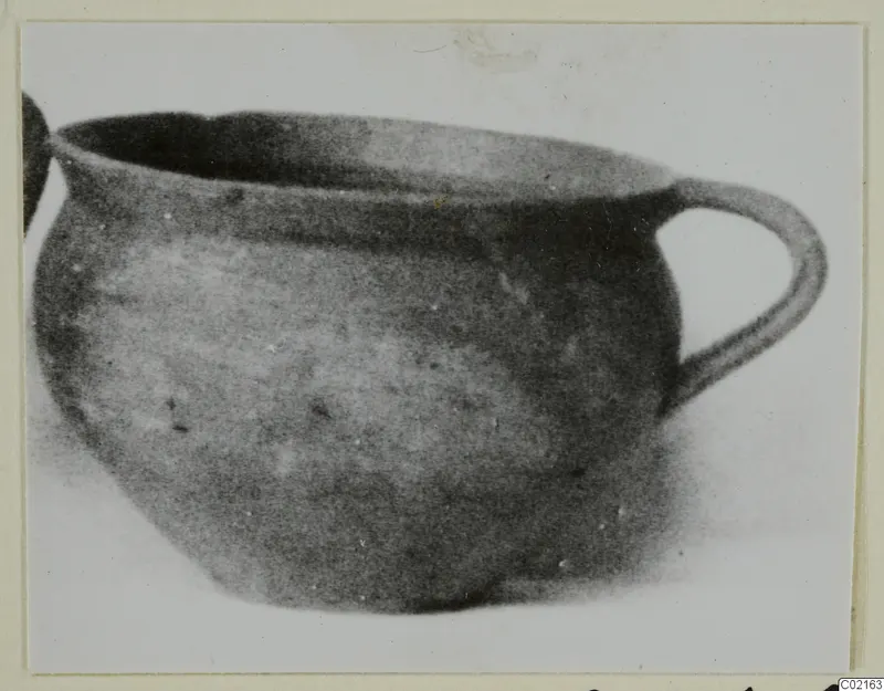 Round vessel with a wide open mouth and a single loop handle, photographed from the side