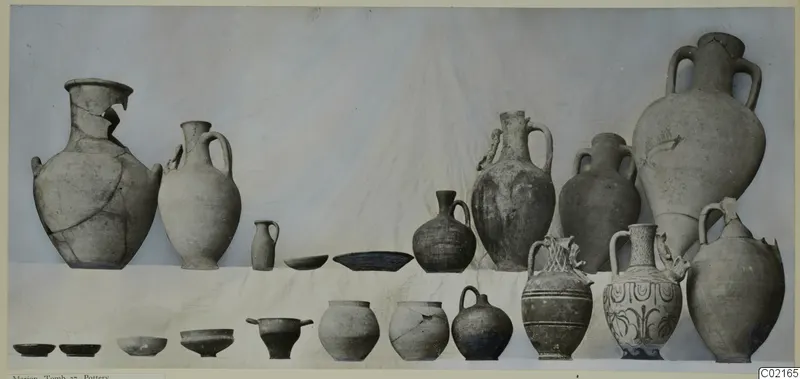 Pottery vessels from Marion, Tomb 37, arranged in two rows against a pale cloth backdrop.