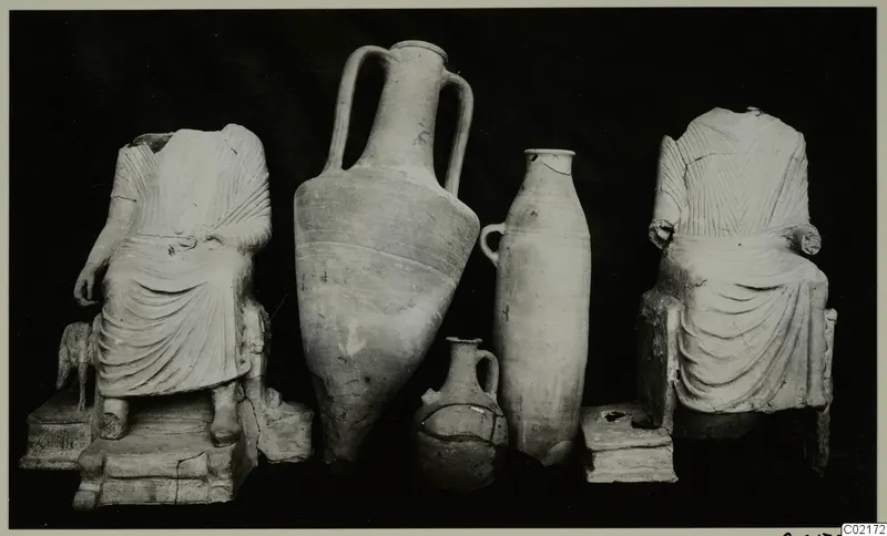 Terracotta statuettes and pots from Marion Tomb 30: two seated headless figures flanking three vessels
