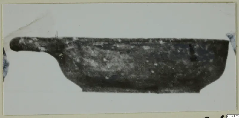 Side view of a dark, shallow Black Slip I-VI vessel with a long horizontal handle projecting to the left