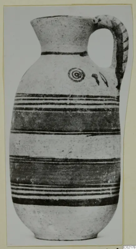 Jug with a strap handle, dark banded decoration and a spiral motif on the shoulder.