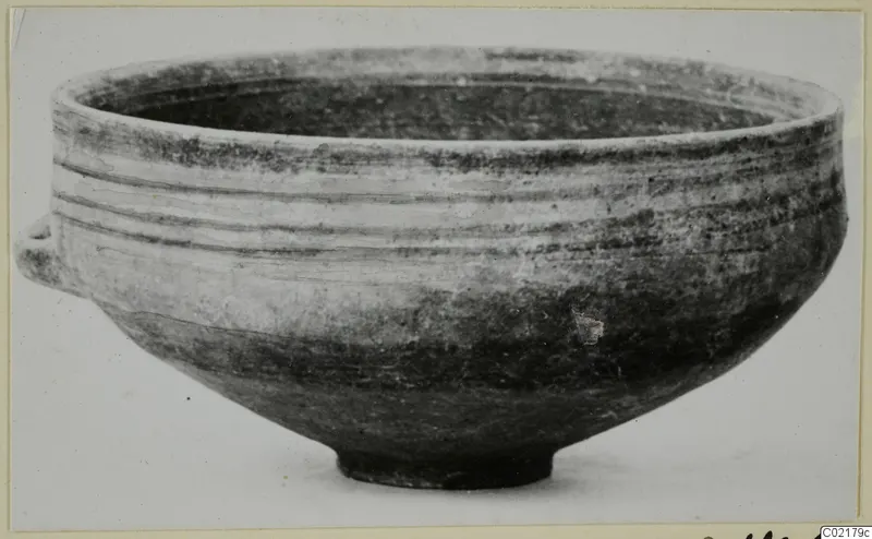 Black-on-Red pottery bowl with a small side lug, shown in side view against a plain background.