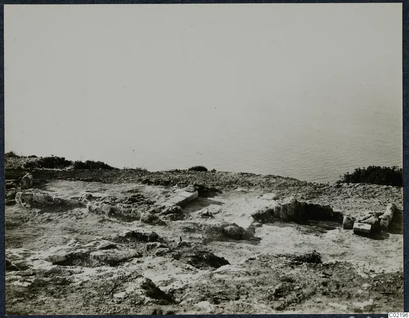 Low stone foundations and ruined walls on a rocky headland at Vouni, with the sea beyond