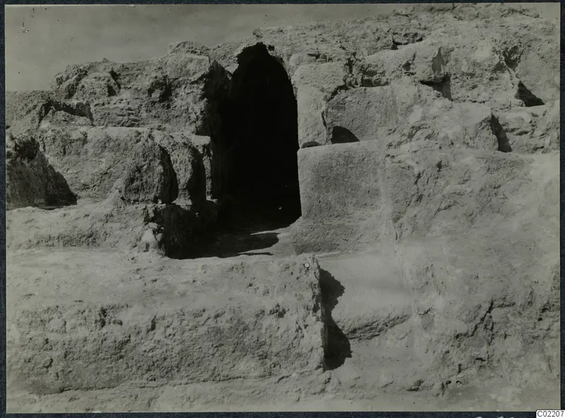 Excavated stone walls at the Vouni palace, with a dark arched opening at centre