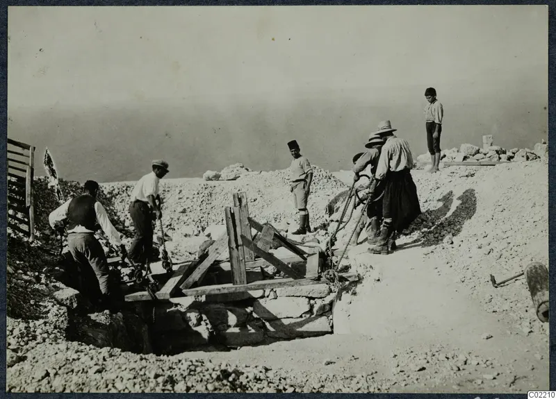 Men and a boy working at the central cistern at Vouni, with timber supports and ropes over the stone-lined pit.