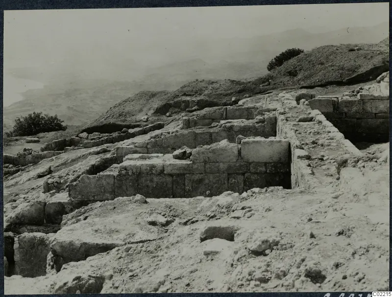 Excavated stone walls on a hillside at Vouni palace, with hills and the sea haze beyond