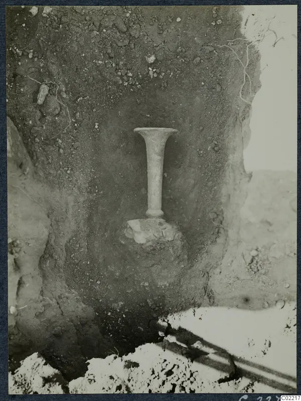 Tall stemmed vessel with a flared rim standing in soil at Vouni Palace, during excavation