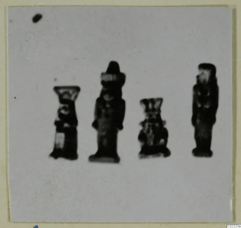Four small dark figurines standing in a row on a pale card mount