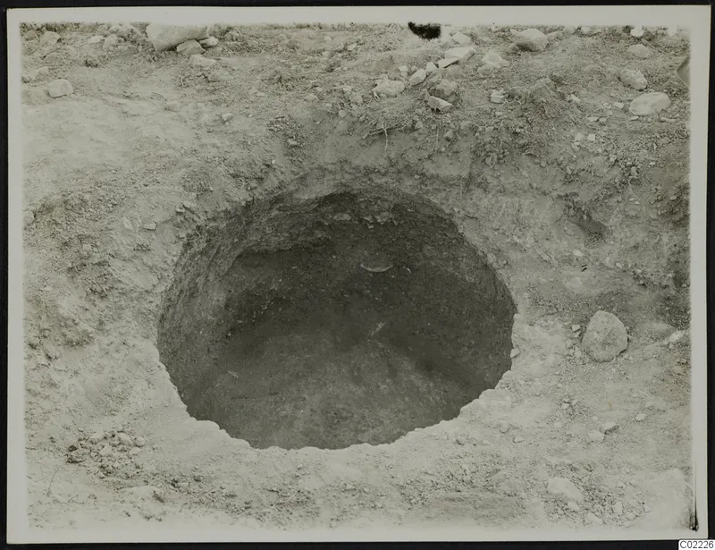 Excavation at Ayios Iakovos: a round pit in sandy soil with scattered stones around it