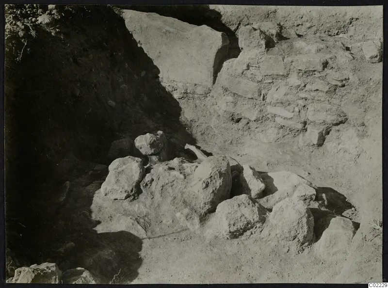Excavation at Ayios Iakovos showing a cluster of large stones against a stone wall and earth bank