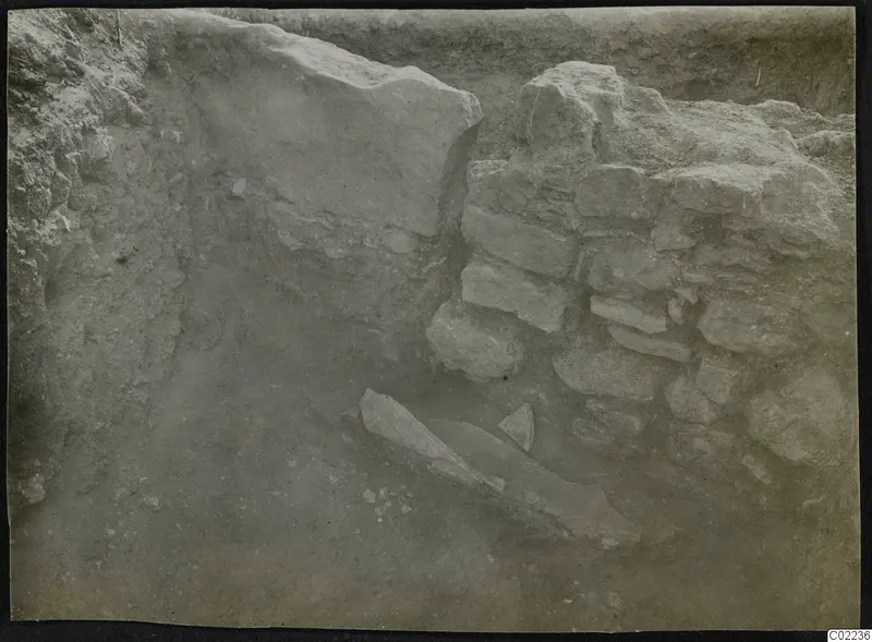 Excavated trench at Ayios Iakovos with a rubble stone wall and a long flat stone slab on the floor