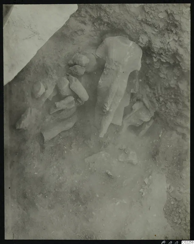 Statues and stone fragments lying in excavated soil at Kition, with a large headless sculpture in the middle.