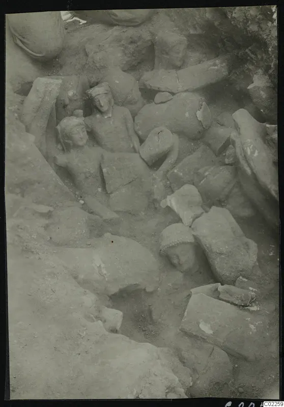 Accumulation of stone statues and heads lying among rubble in an excavated corner at Kition