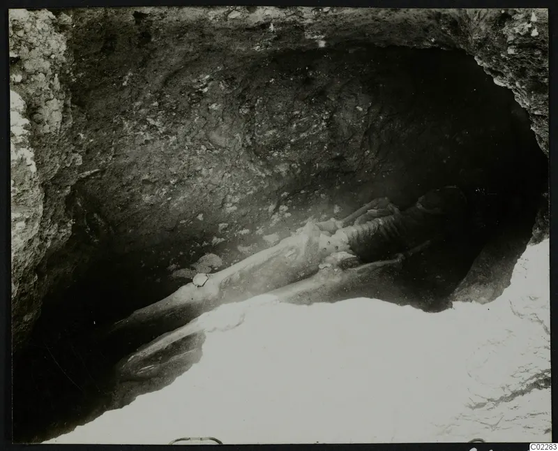 Skeleton lying extended in a rock-cut hollow at Amathus, with stones beside it.