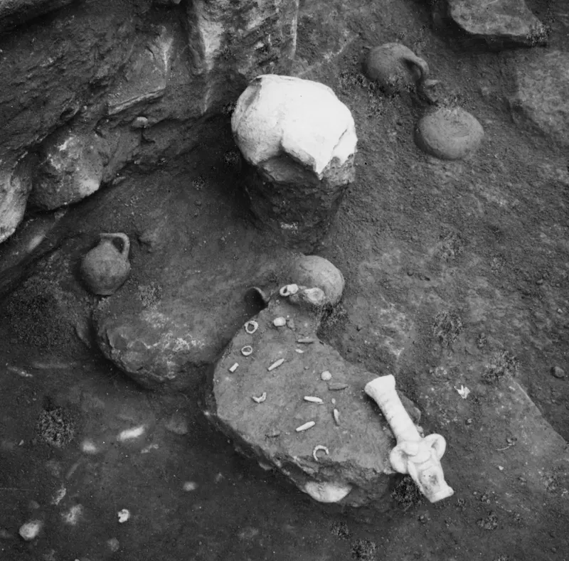 Finds in situ in Tomb 11 at Amathus: small jugs, a pale vessel and a pale object on a dirt floor