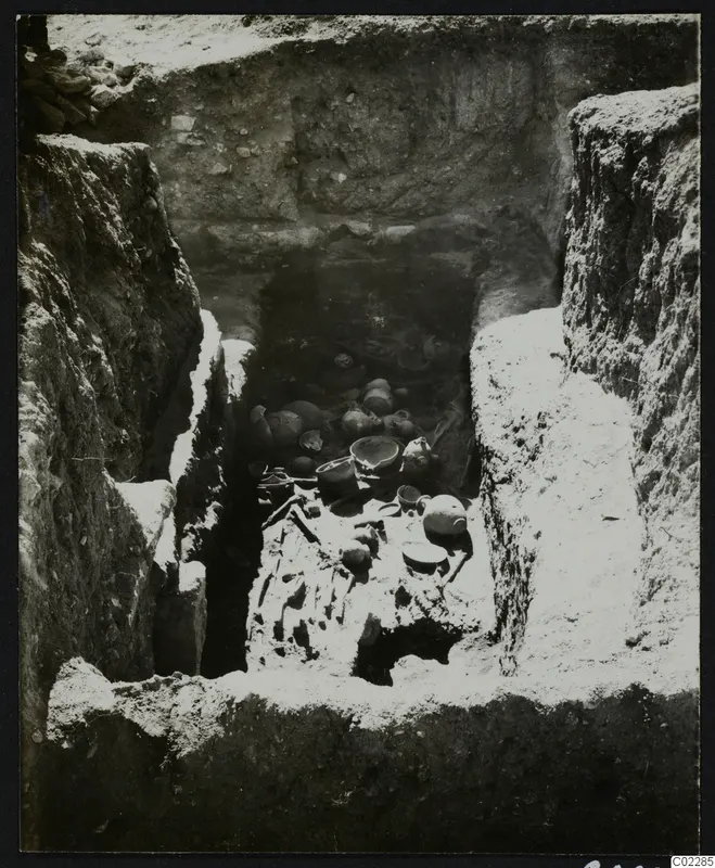Amathus tomb during excavation, with a skeleton and pottery vessels lying on the floor of the chamber