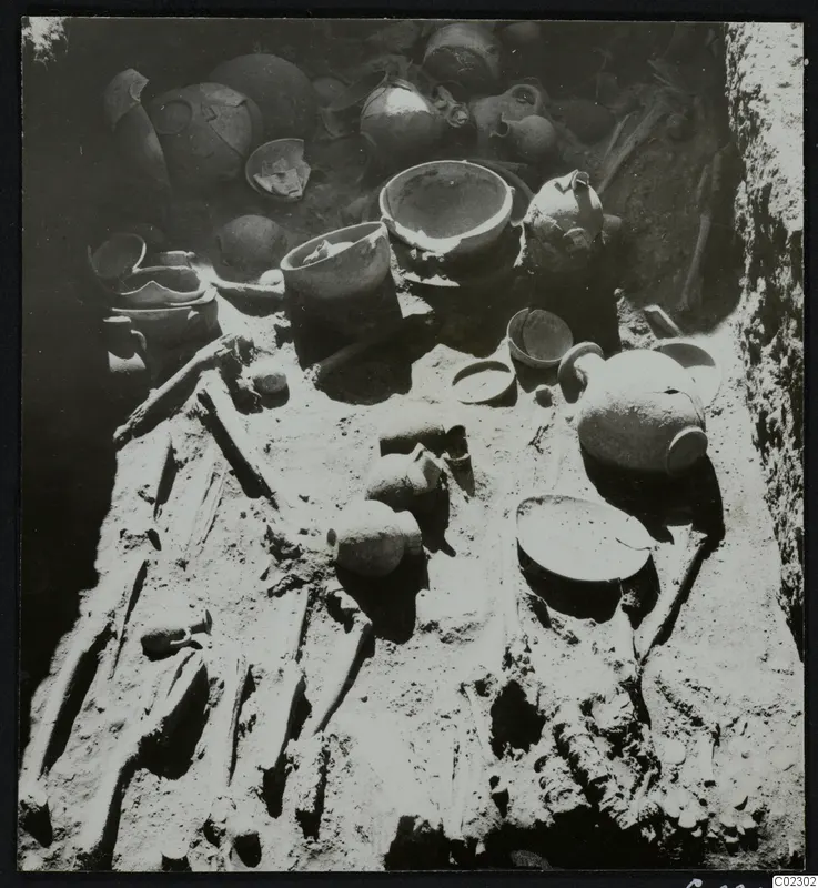 Skeleton and pottery vessels on the floor of a tomb during excavation at Amathus