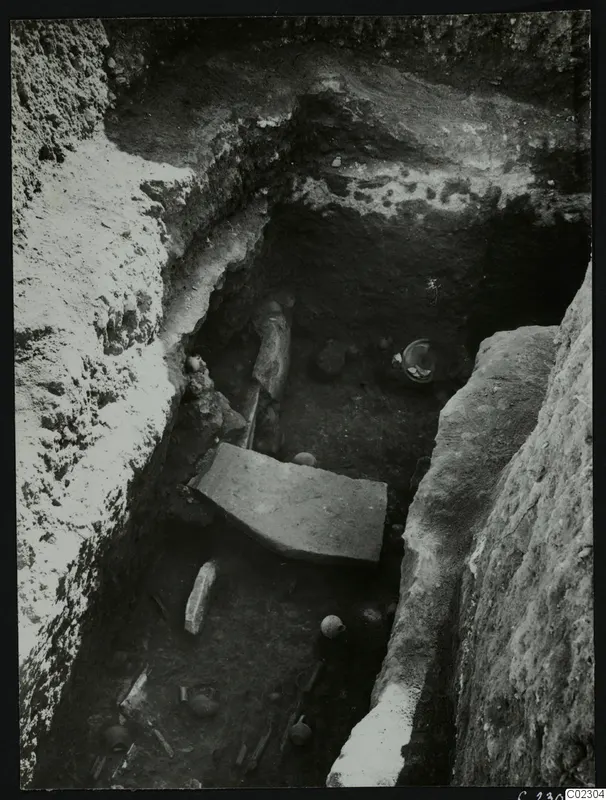 Excavation trench at Amathus with pottery vessels and large stone slabs lying in the cut