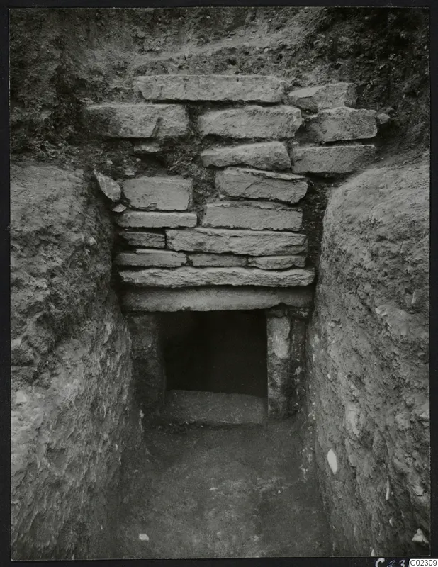 Tomb 24 at Amathus: a cut passage leading to a stone-blocked wall with an open doorway into the tomb chamber.