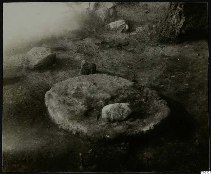 Excavated stone construction at Kythrea: a rounded, stone-edged feature in soil with scattered stones around it.