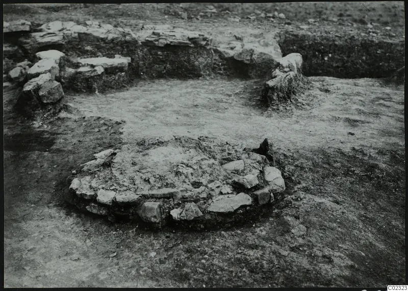 Excavation at Kythrea showing a low circular stone structure in the foreground and stone walls behind it