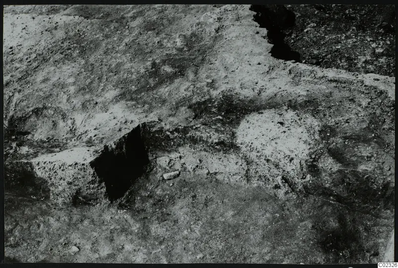 Excavated ground at Kythrea with pale stones and a dark cut in the soil