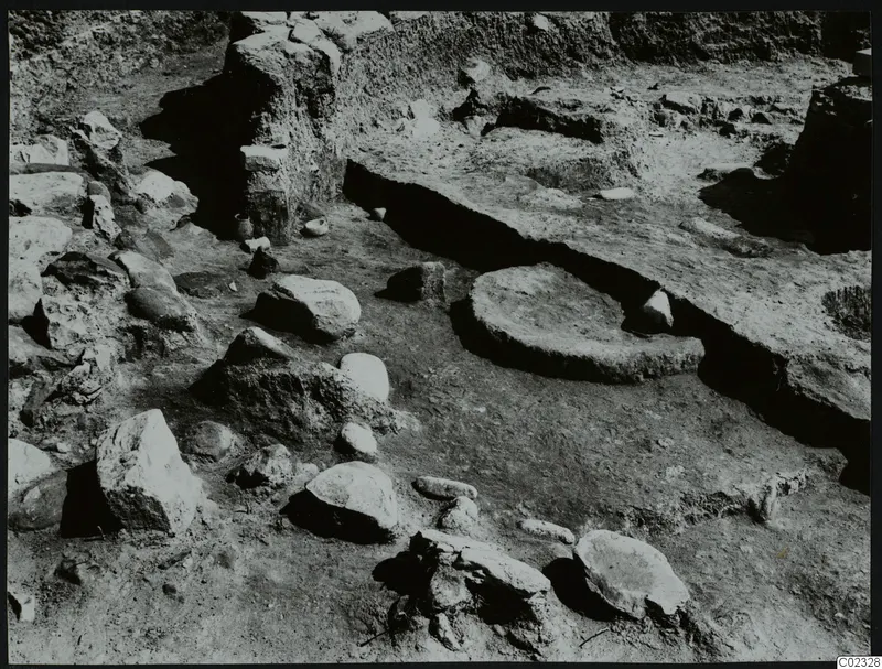 Excavation at Kythrea showing a stone construction, with a rounded stone base and scattered stones in a trench.