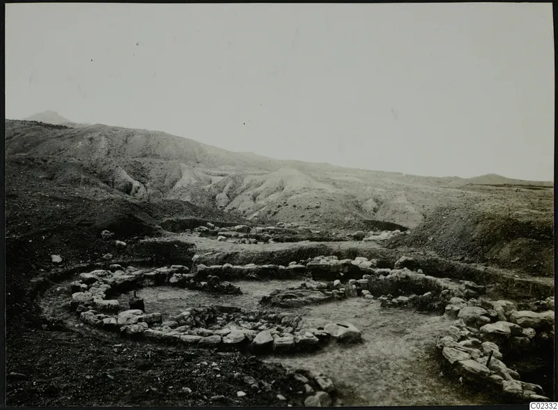 Excavation at Kythrea with low stone walls in a shallow trench, with bare hills rising behind