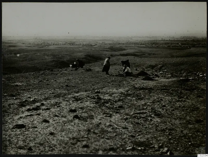 Rocky hillside at Kythrea with several people on the ground and a distant plain with trees