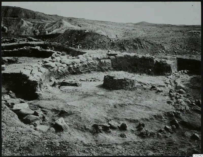 Excavated stone walls and foundations at Kythrea, with spoil heaps and hills in the background.